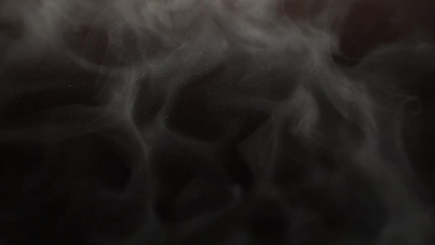 Gray smoke moves slowly around a black background