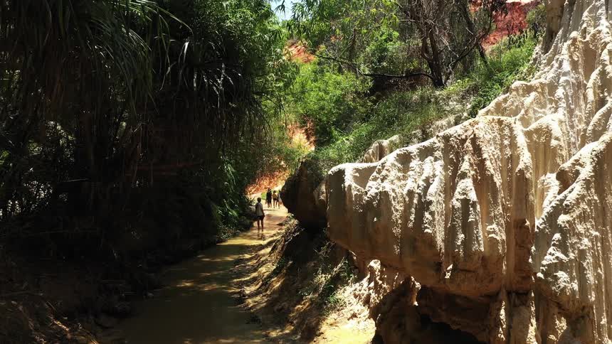 Tourists walking on a river next to rock outcrops