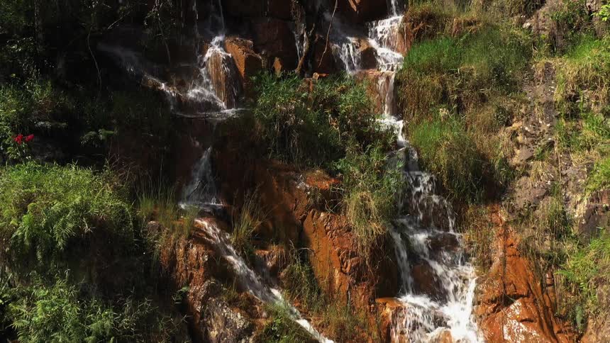 Aerial of a mountain waterfall on a sunny day