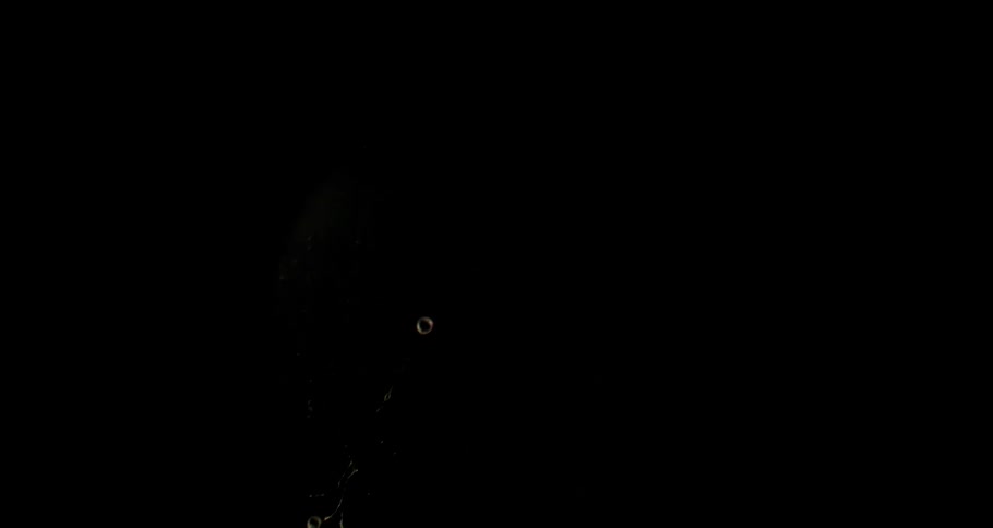 Closeup of a bubble bursting against a black background in slow motion