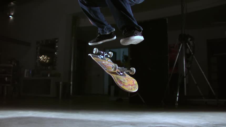 Man jumping in a skateboard trick inside a studio