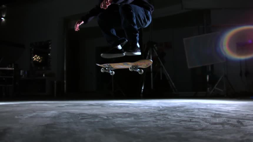 A boy doing a skateboard trick in a garage at night
