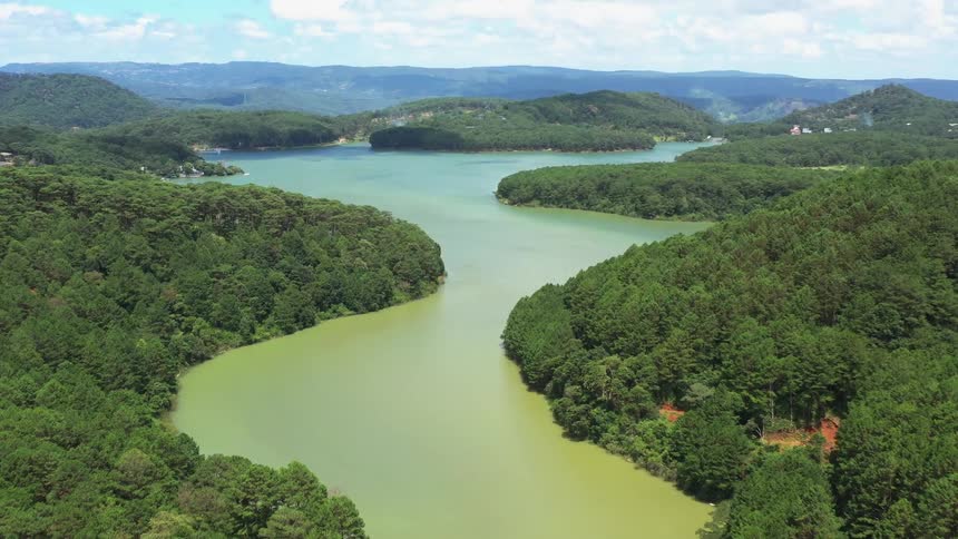 Landscape of a greenish river surrounded by forested hills