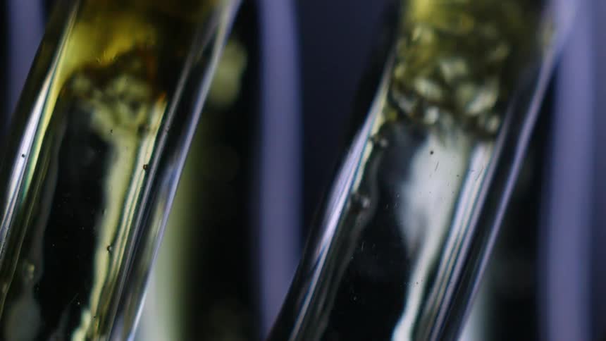 Extreme closeup of glass vials with colorful liquid flowing through
