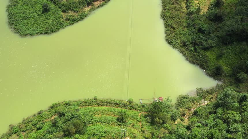 Downward view of a greenish river amidst shores and hills