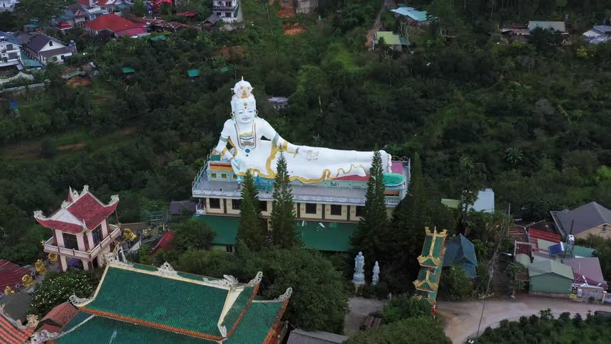 Aerial of a buddhist statue in a temple in a neighborhood surrounded by nature