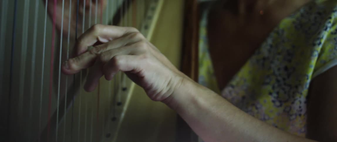 Closeup of a womans hands playing the harp