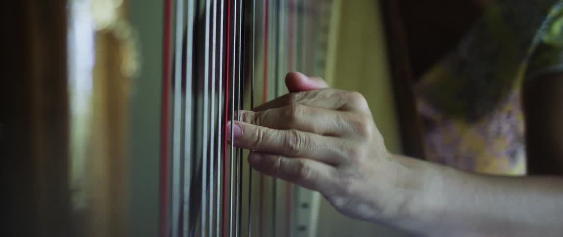 Closeup of a womans hands playing the harp