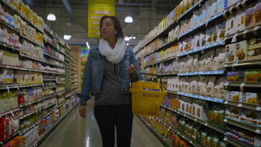 Woman shops in a grocery store with a hand basket