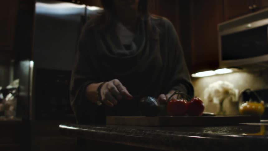 A woman pulls some vegetables from the fridge