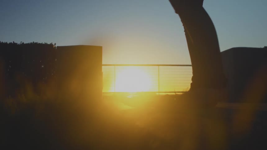 A person walks away from a railing before turning back towards the sunset