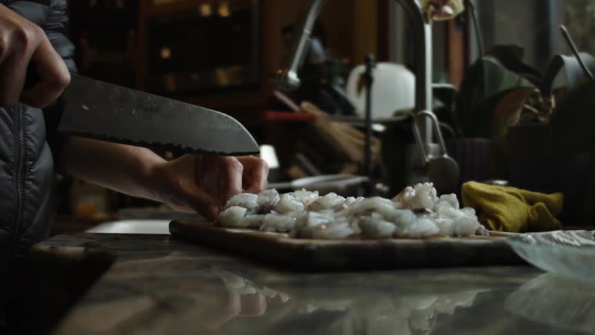 A knife is used to cut raw meat on a cutting board