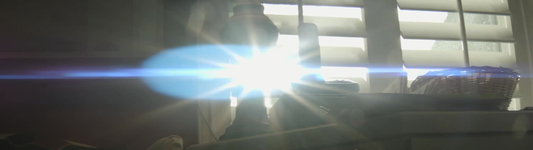 The sun shines in through the blinds of the window in this room