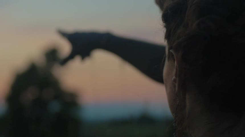 A man and woman stand outside together at sunset