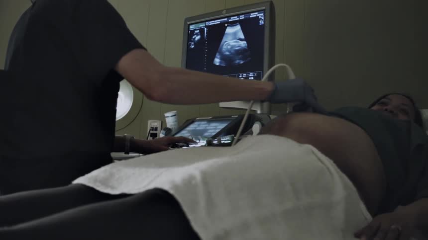 A pregnant woman is getting examined by a device
