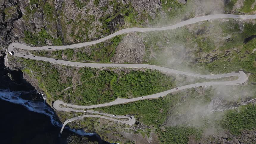 An aerial view of a road that climbs a hill in several curves