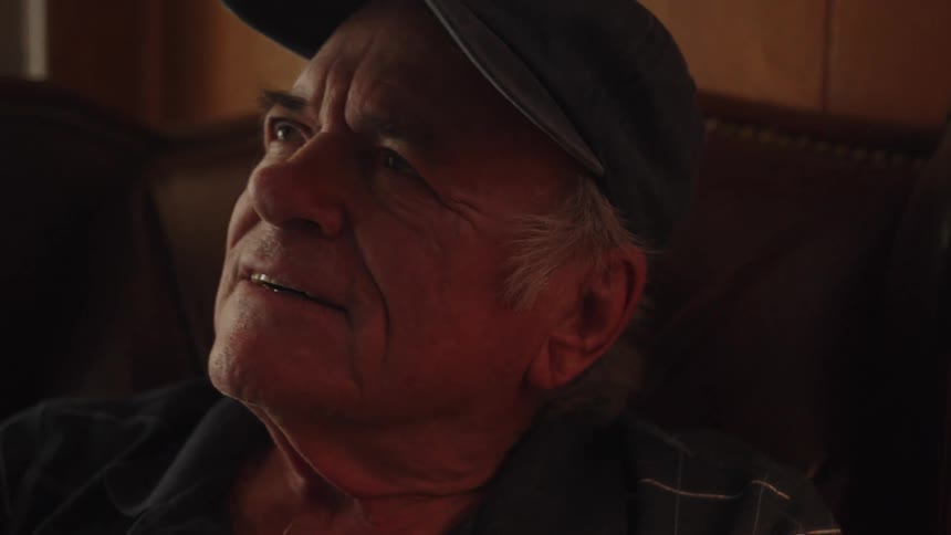 Portrait of an elderly person sitting in an armchair looking up with a facial expression of happiness