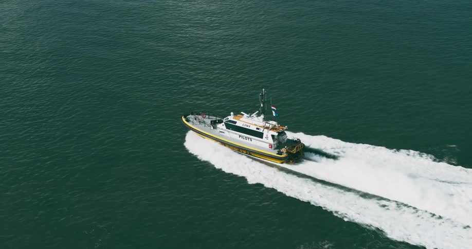 A ship leaves a splashing trail as it sails across the water