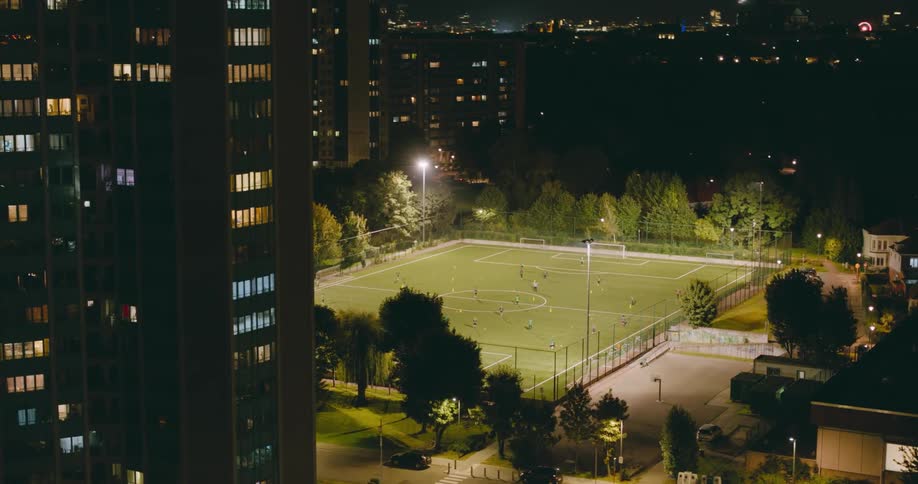 Panorama of a football field amidst the buildings of a metropolis at night