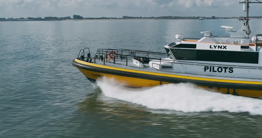 Lynx pilots boat motors across water leaving a churning wake on a cloudy day