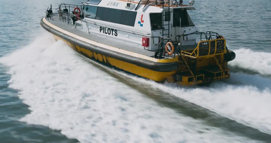 A ship leaves a splashing trail as it sails across the water