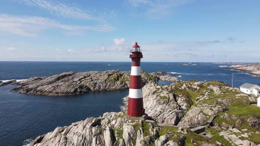 A clip of a light house on a rock at the shore