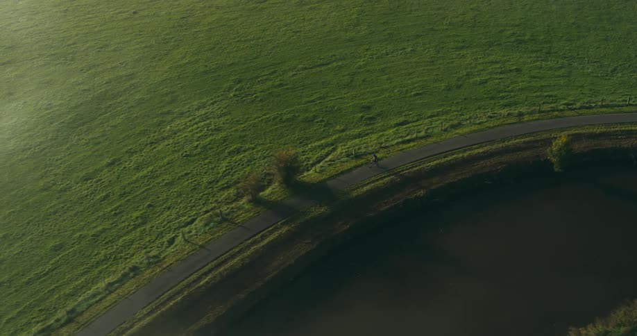 A person pedals a bicycle in a rural landscape on a sunny morning