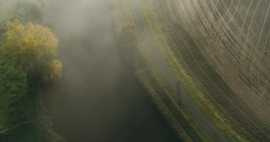 A person riding a bicycle in a rural landscape on a sunny morning