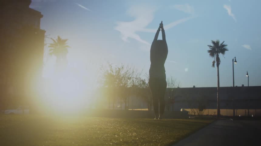 A woman is stretching as the sun rises