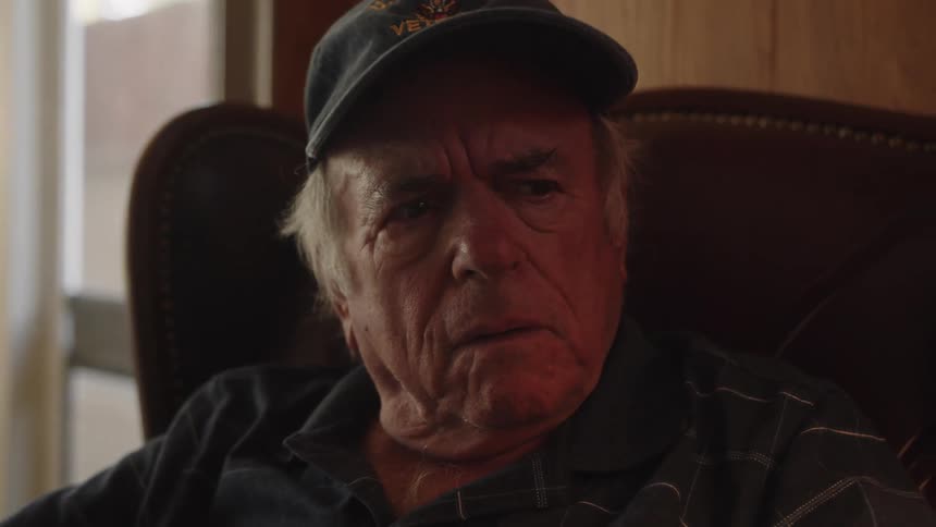 Portrait of an elderly man sitting in an armchair reading a newspaper