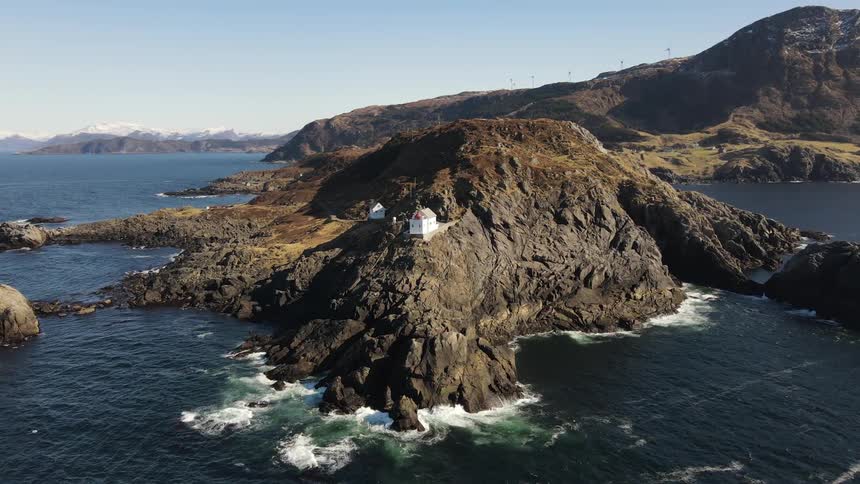 A white house on top of a stone mountain facing the sea