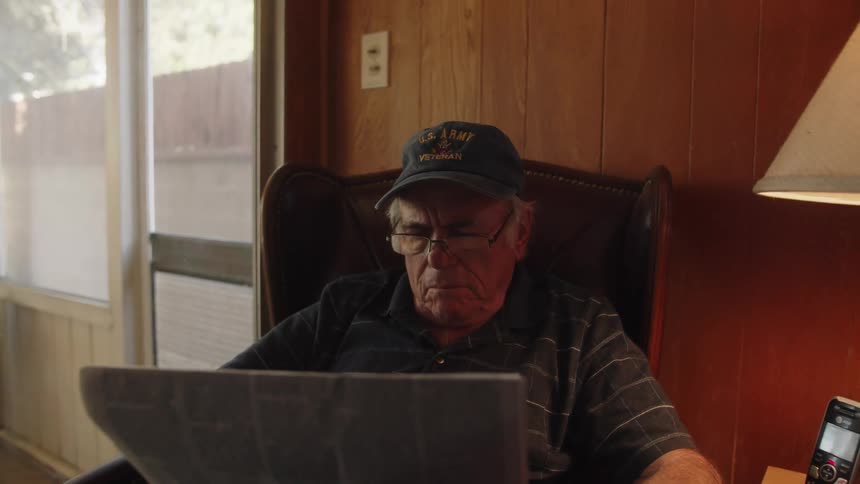 Portrait of an elderly person sitting in an armchair reading a newspaper