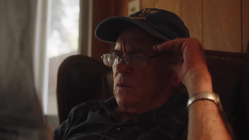 Elderly person sitting in an armchair and reading a newspaper with a surprised expression
