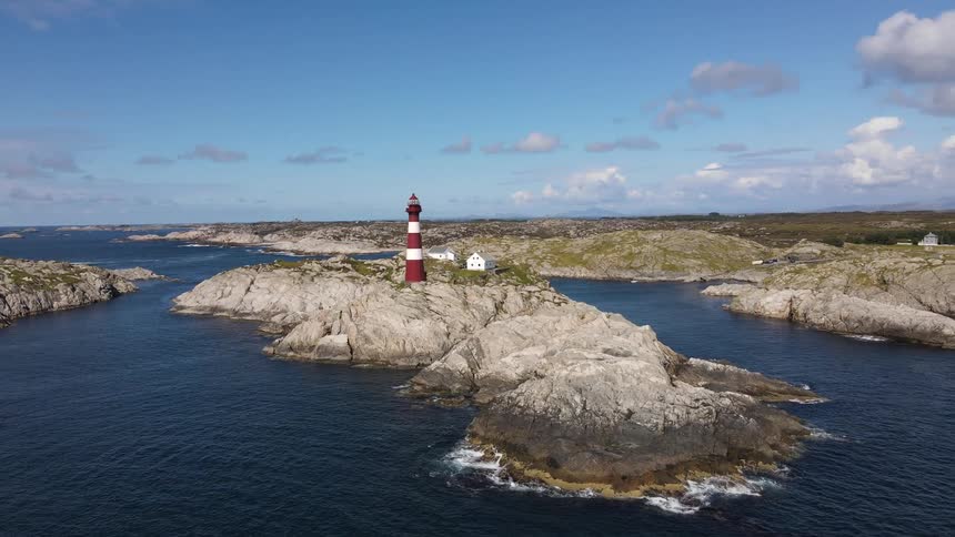 A red lighthouse on top of a stone island surrounded by water