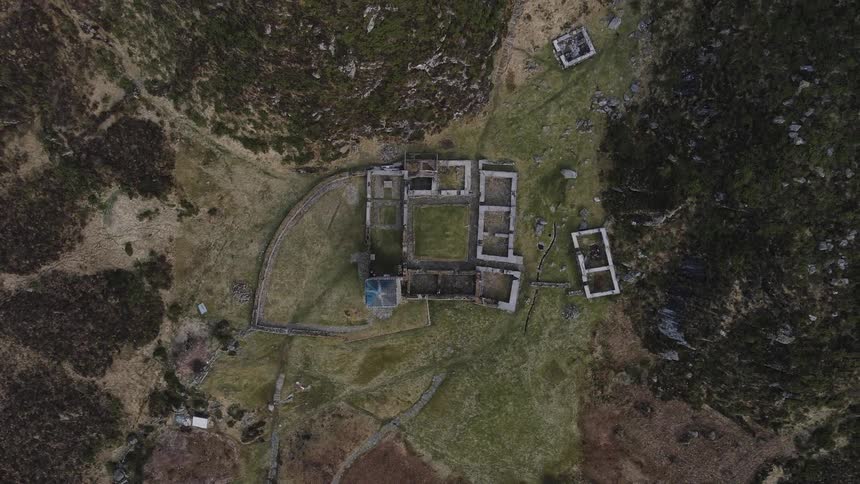 Aerial view of a stone fortress on a hill beside mountains