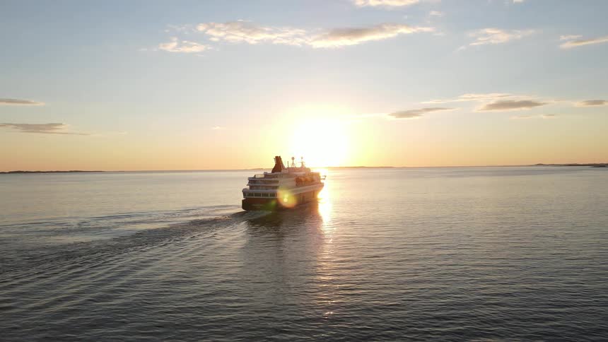 A vessel sailing in a sea with sunset light