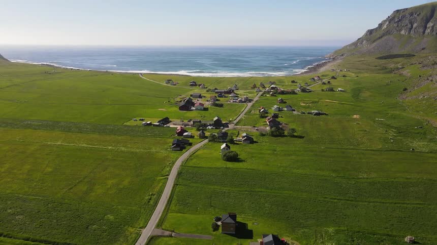 Aerial panorama of houses in the middle of a grassland and facing the sea