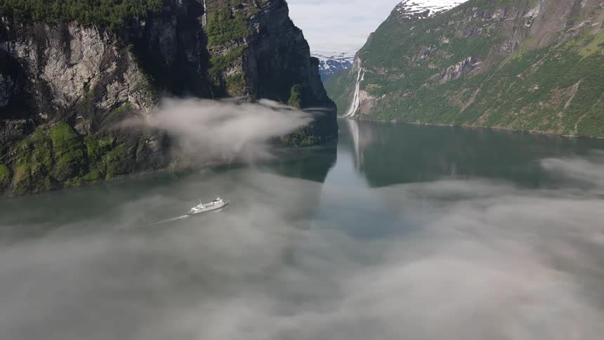 Aerial panorama of a boat passing through a river amidst mountains