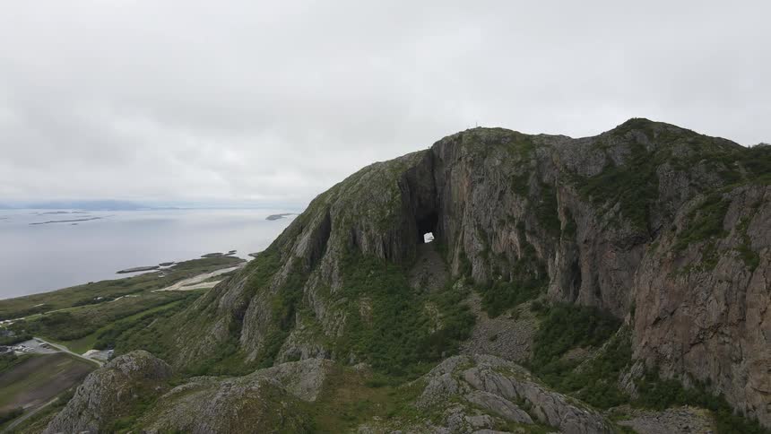Aerial panorama of a mountain with peaks by the sea on a cloudy day