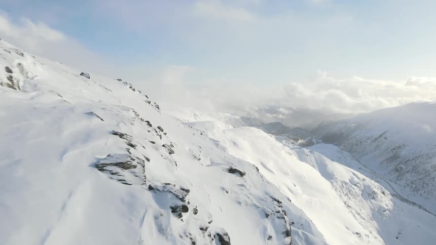 Aerial of frozen mountain range during winter on a sunny day