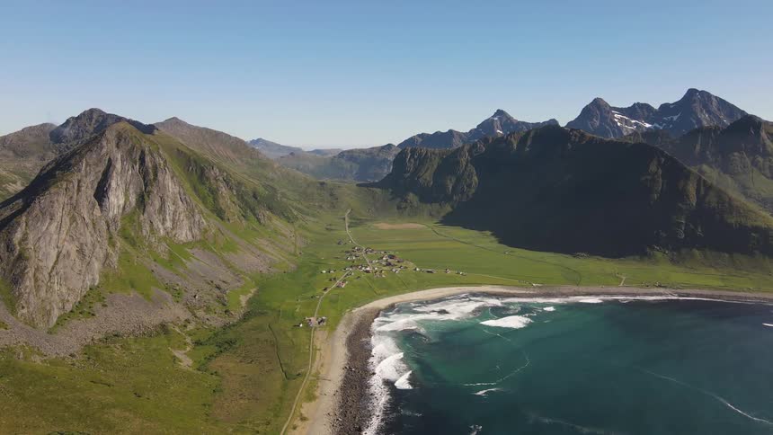 Aerial of a small town on the coast of a beach surrounded by mountains