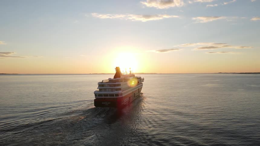 The ms nordkapp sailing over ocean waters casting a tranquil scene as the sun sets