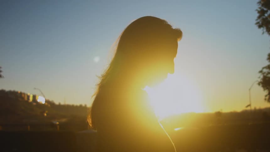 A woman looking down near a clear sky at dawn