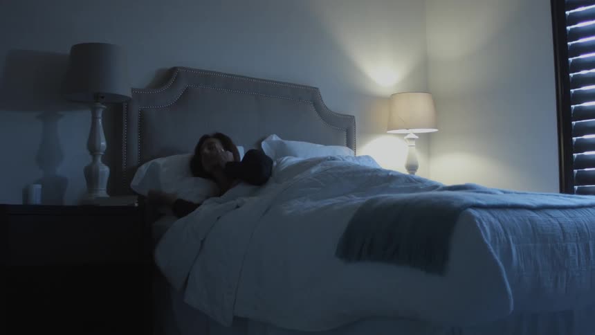 A person gets up from sleeping and turns the light on