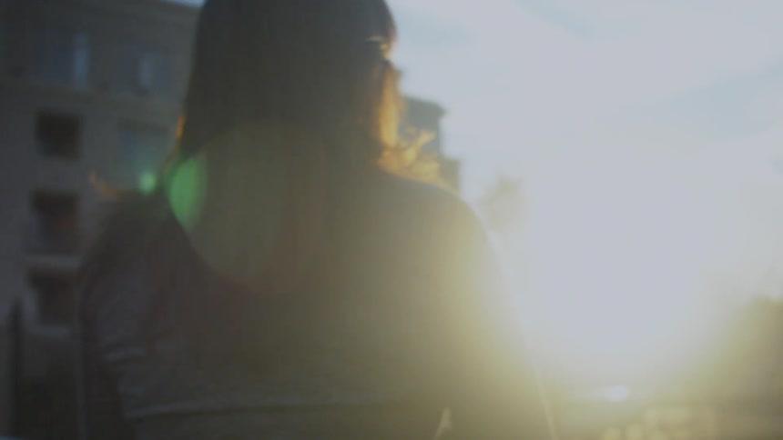 A woman beings walking towards the sunset
