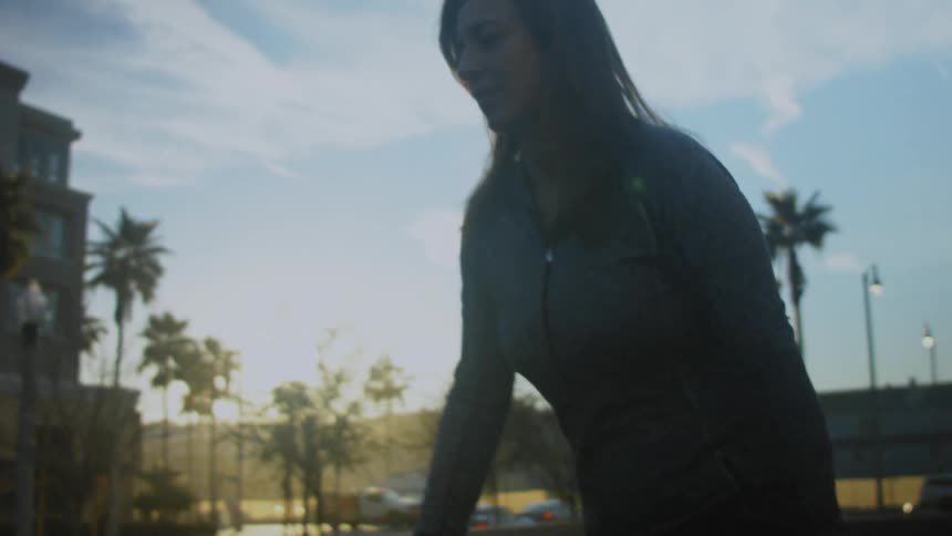 Light shines over buildings as a woman walks