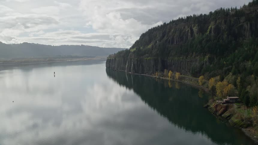 Panorama of a landscape with a lake next to a mountain with forests on a morning day