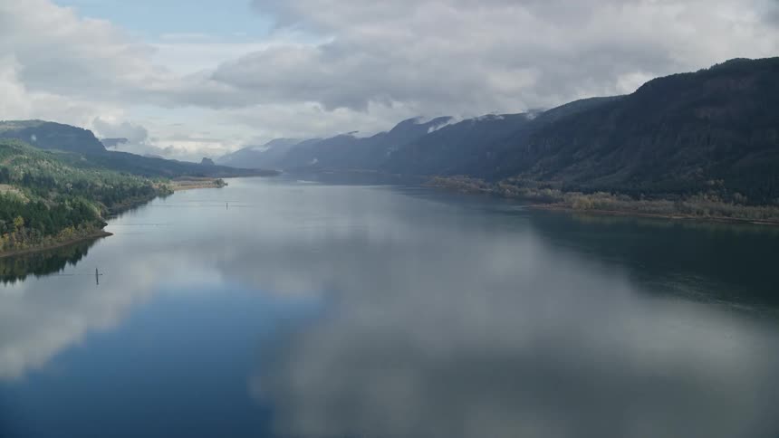 Panorama of a lake surrounded by mountains on a cloudy sky day