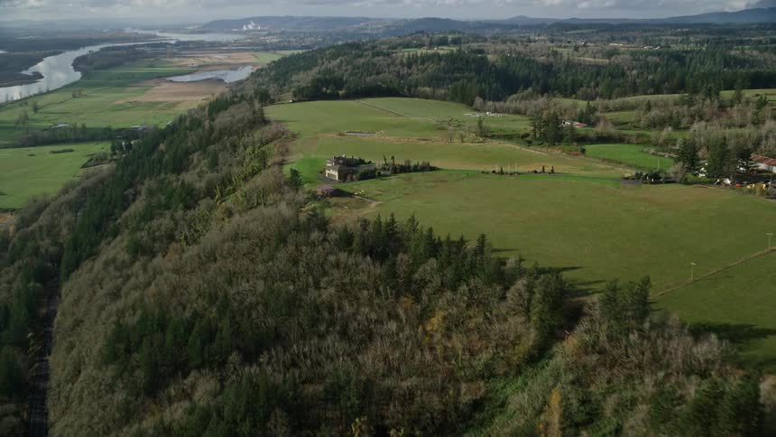 Panorama of a house amidst grasslands on a mountain facing a lake