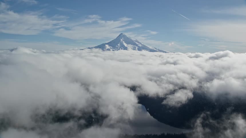 Aerial view through clouds snow covered mountain peak